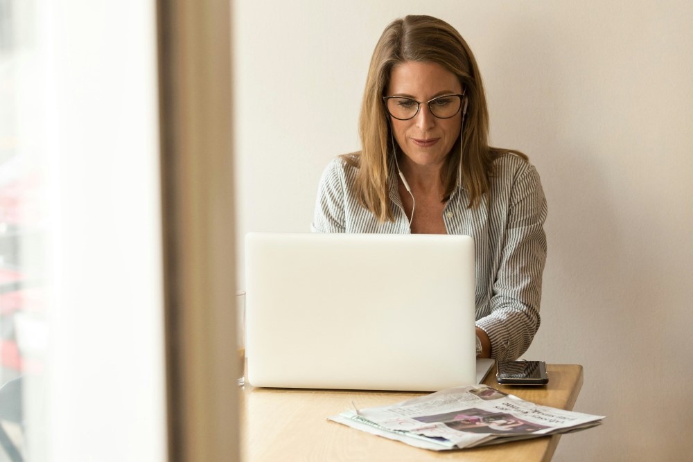 A woman posting at the desk with a laptop